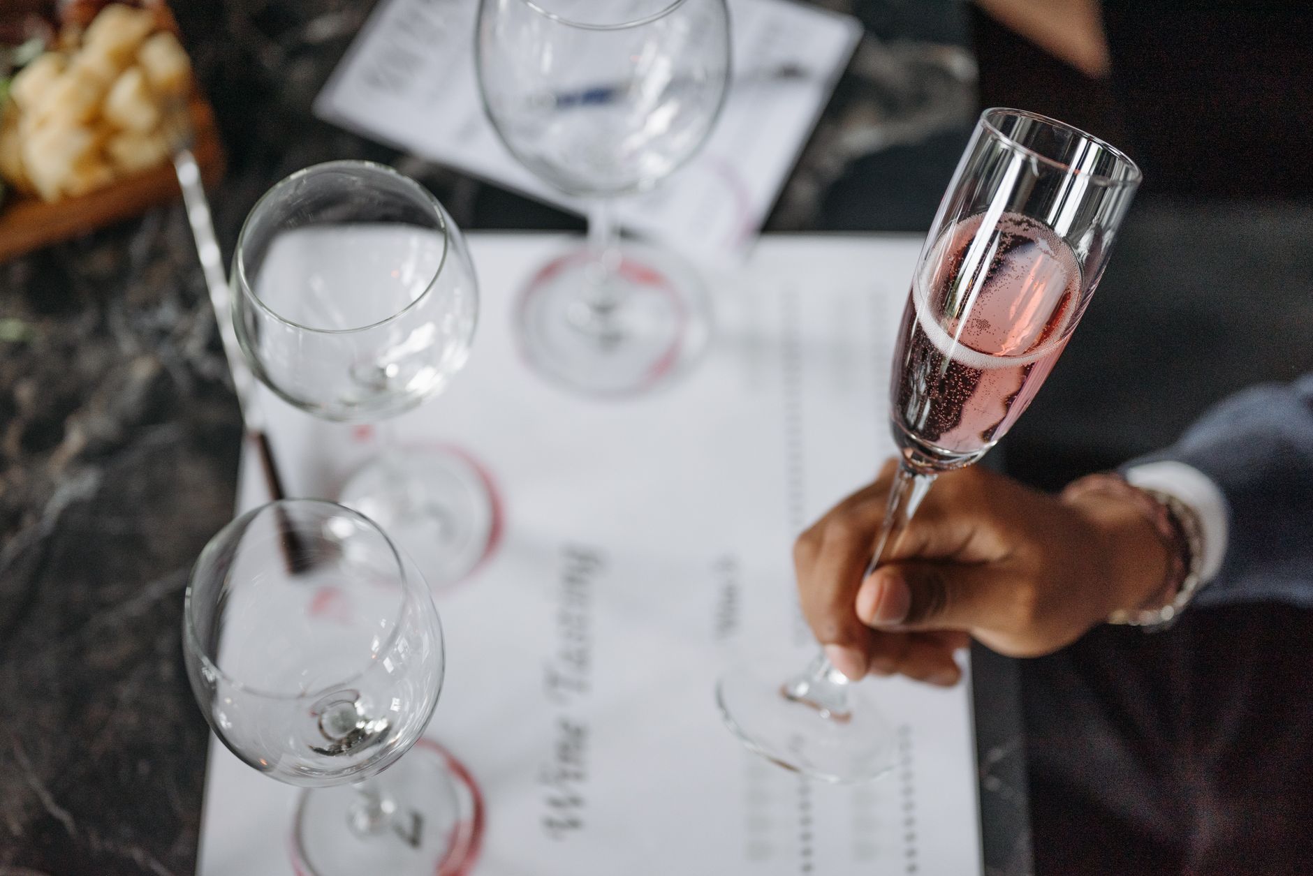 A close-up of a wine tasting setup with glasses and a hand holding champagne.