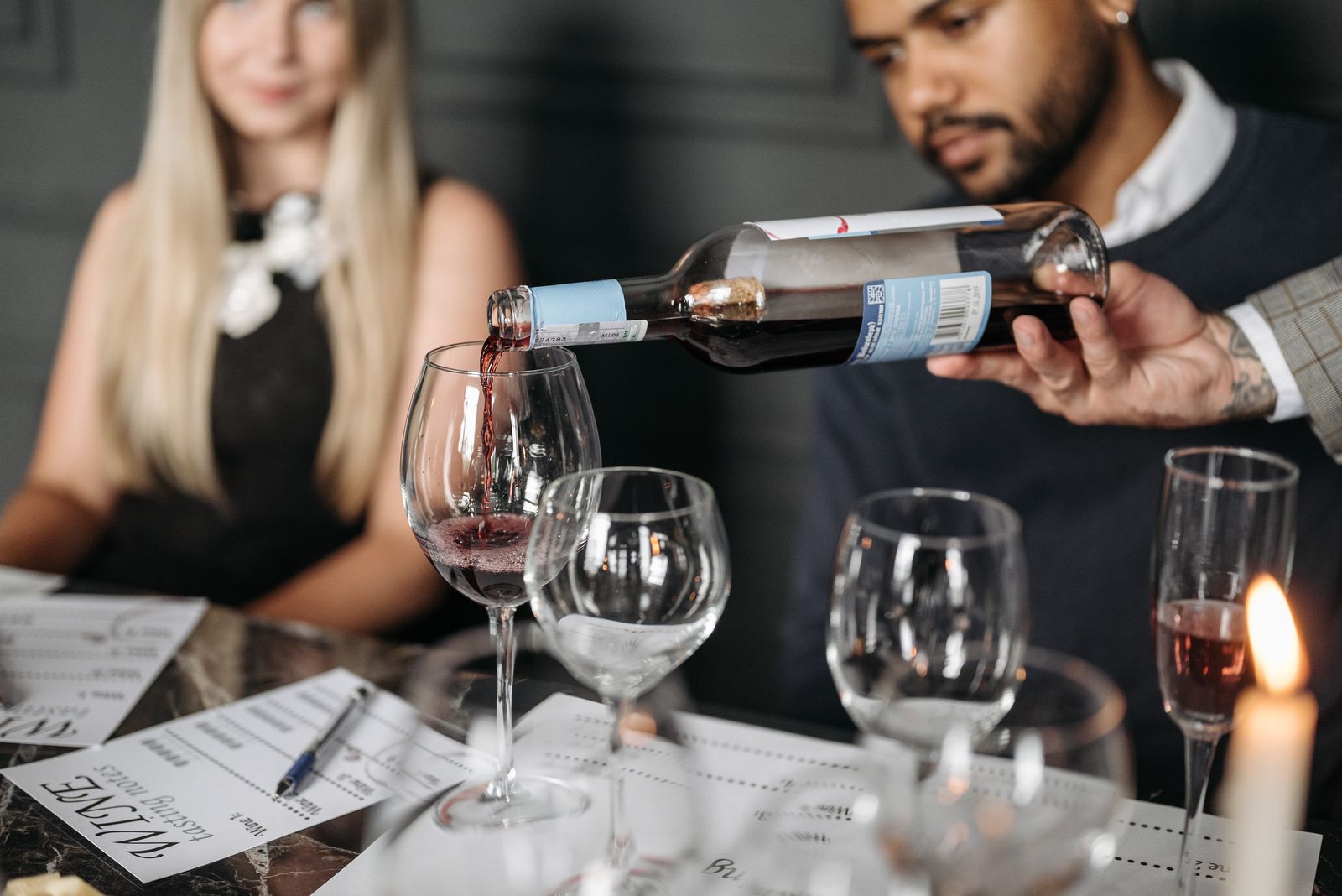 Sommelier sirviendo vino en una mesa a la luz de las velas