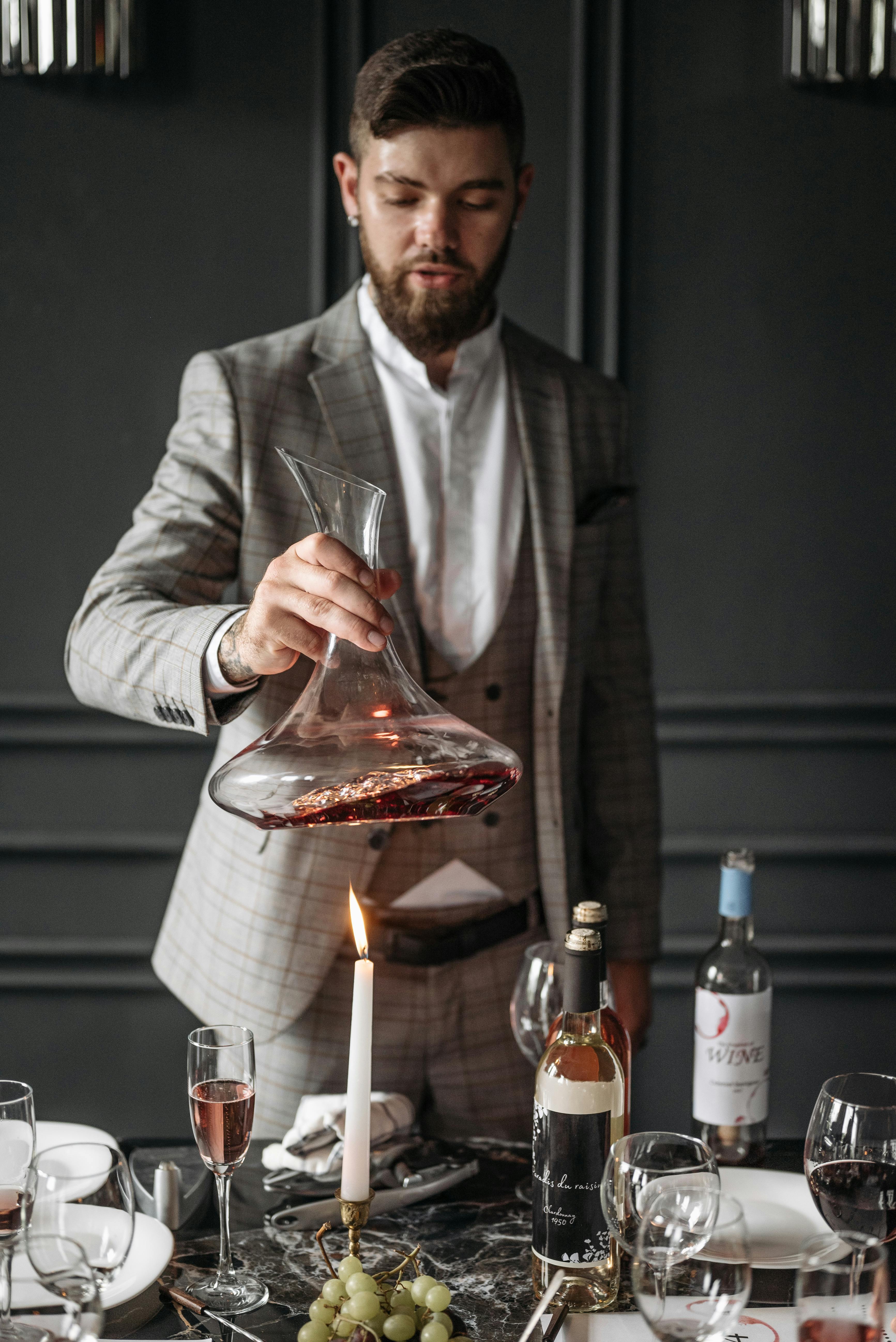 Stylish man in suit holding a decanter, setting a classy dinner atmosphere.