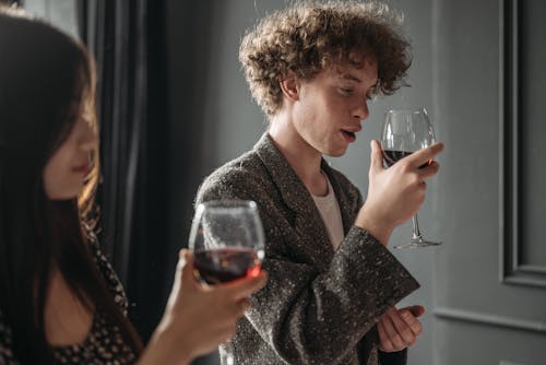 A Man and a Woman Holding Goblet Glasses with Red Wine