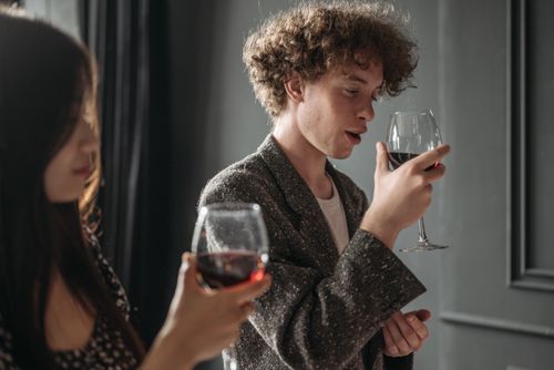 Free Curly-haired man and woman with glasses enjoying red wine indoors. Stock Photo