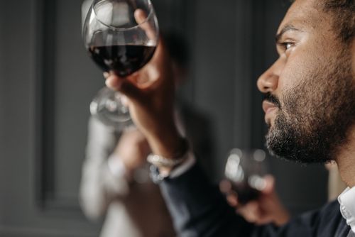 Free Close-up of a man admiring a glass of red wine indoors, showcasing a moment of elegance. Stock Photo
