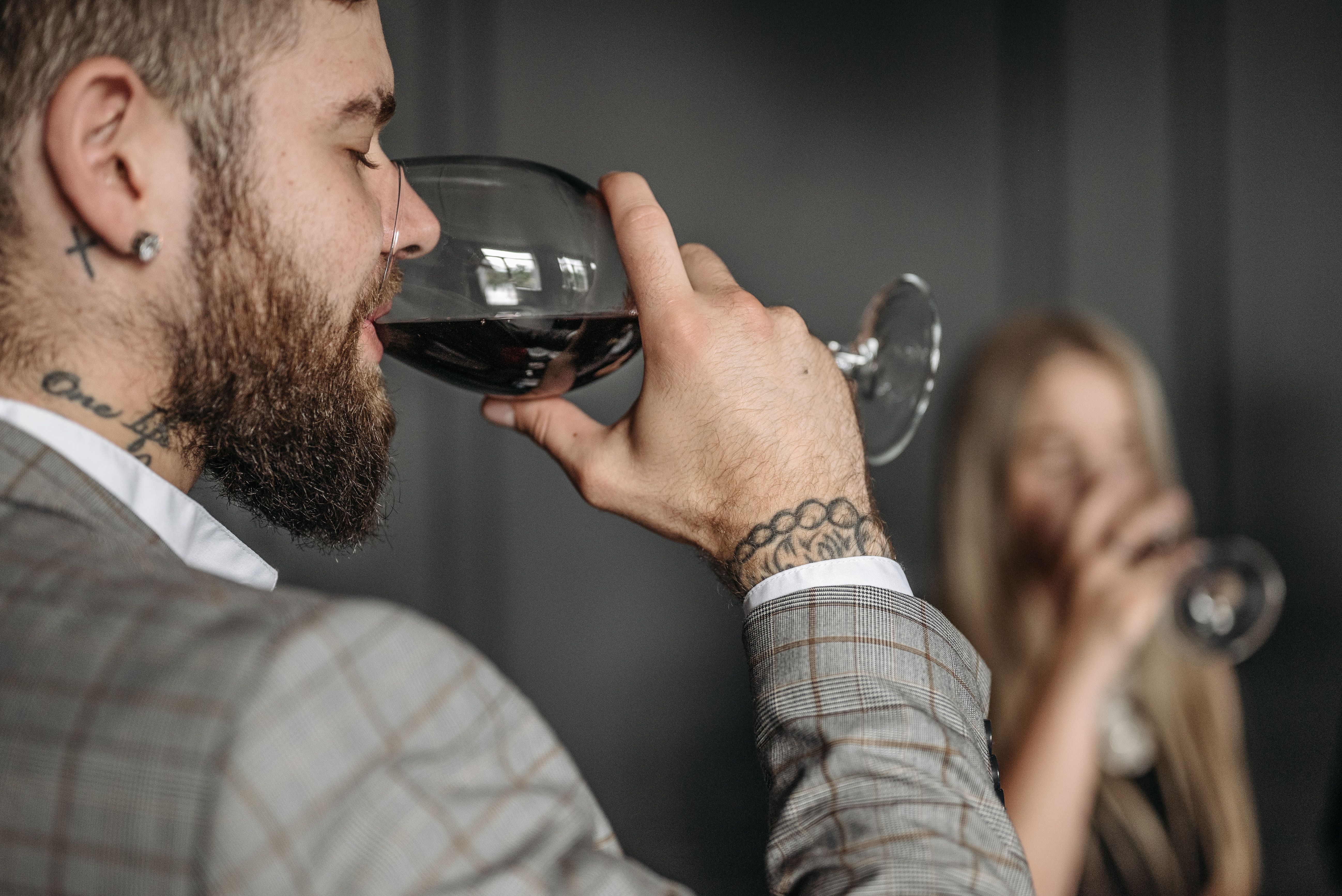 Man savoring red wine indoors, highlighting an elegant lifestyle with a focus on detail.