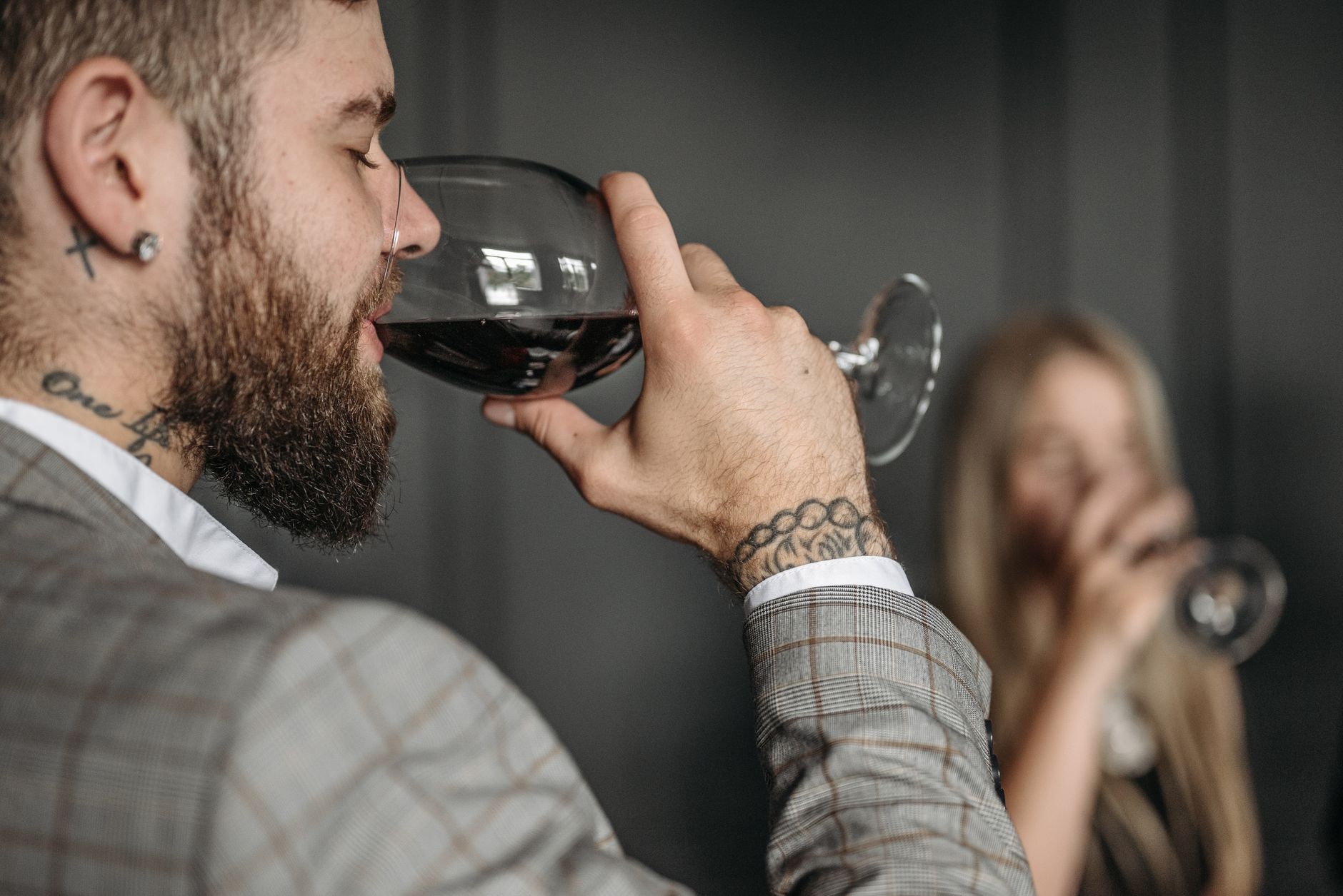 Man savoring red wine indoors, highlighting an elegant lifestyle with a focus on detail.