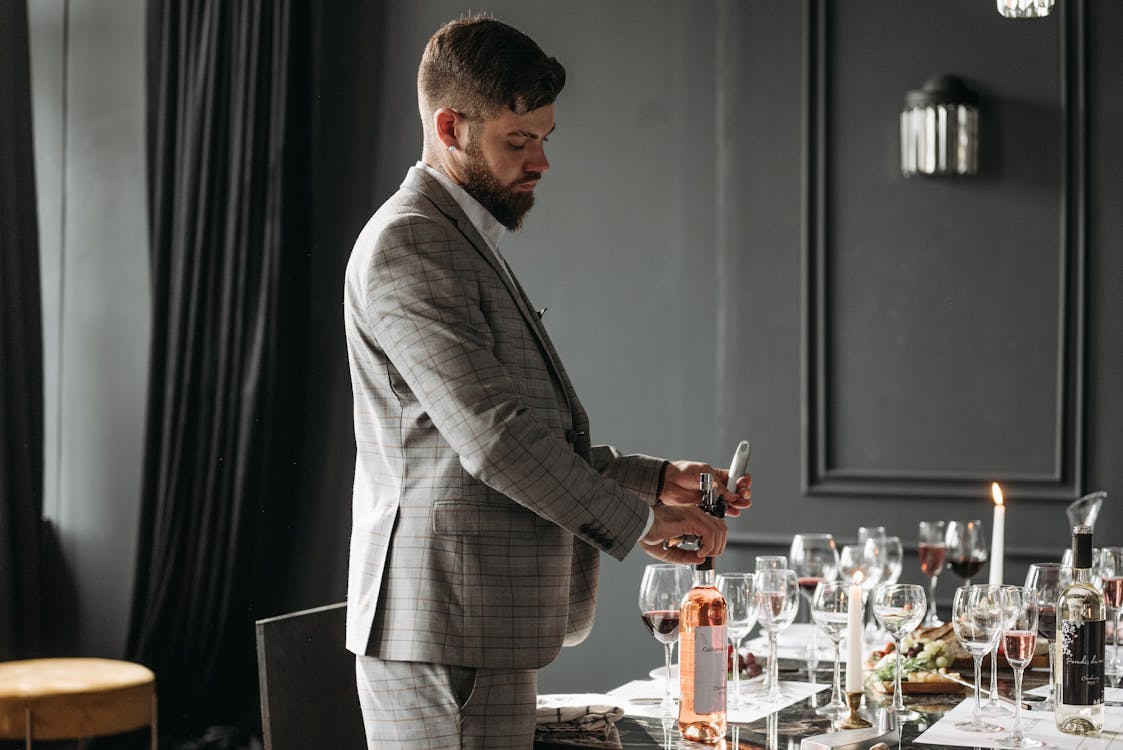 A Man in Gray Suit Opening a Wine Bottle