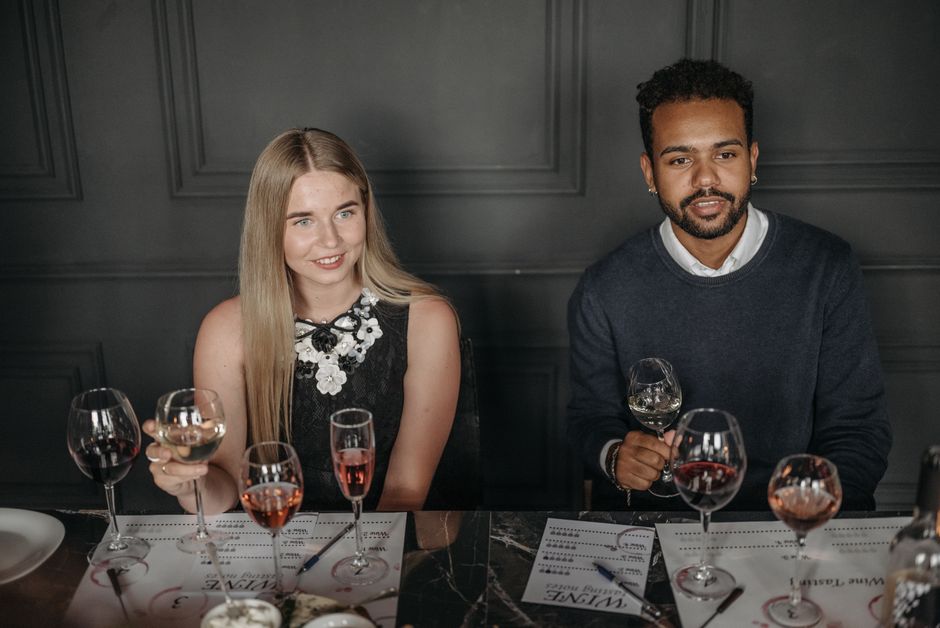 Two adults enjoying a wine tasting session in a sophisticated indoor setting.