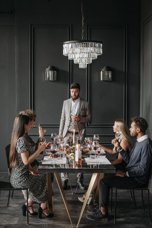 Free People Sitting at the Table Holding Wine Glasses Stock Photo