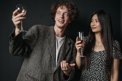 Man in a Gray Blazer and a Woman in Floral Top Holding Glasses of Wine