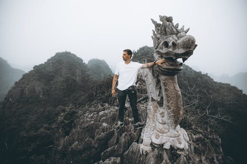 Man Touching a Dragon Sculpture at Mua Cave, Ninh Binh, Vietnam 