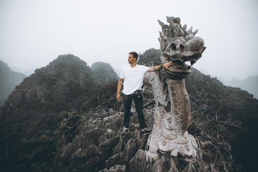 Man poses with a dragon sculpture atop Mua Cave, amidst the stunning limestone peaks of Ninh Bình, Vietnam.