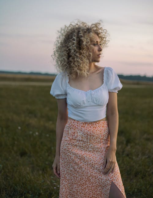 Free A Blonde Woman with Curly Hair Wearing a White Blouse Stock Photo