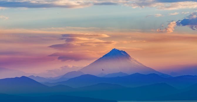 A breathtaking view of a mountain silhouetted against a colorful sunrise sky.