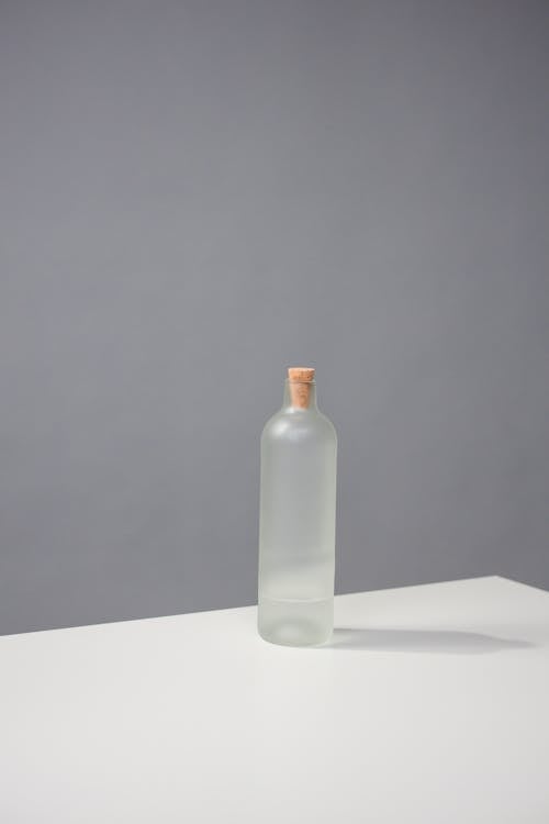 Foto profissional grátis de dentro de casa, fundo cinza, garrafa de vidro