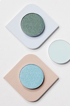 Top-down view of colorful eyeshadow palettes on a white surface with copy space.