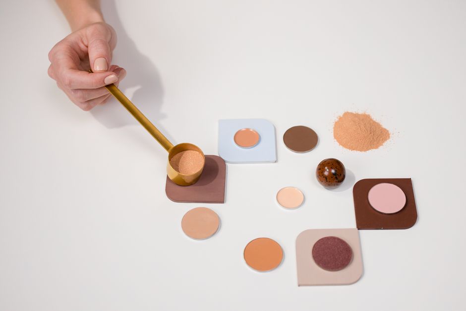 Flat lay of makeup powders and palette with a hand holding a brush for beauty concepts.