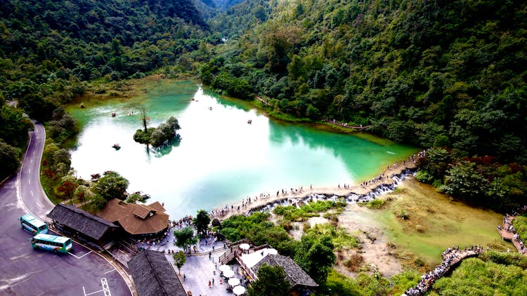 People On Paths Near Lake Between Hills