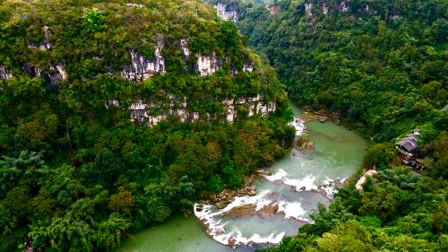 Free Aerial view of a lush gorge and river in Anshun, Guizhou, China, surrounded by dense forest. Stock Photo