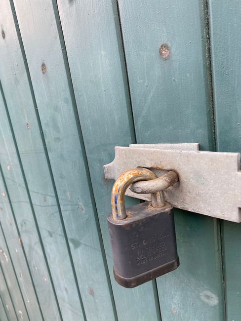 Fotomural Un candado envejecido en una puerta de madera verde, simbolizando seguridad y protección.
