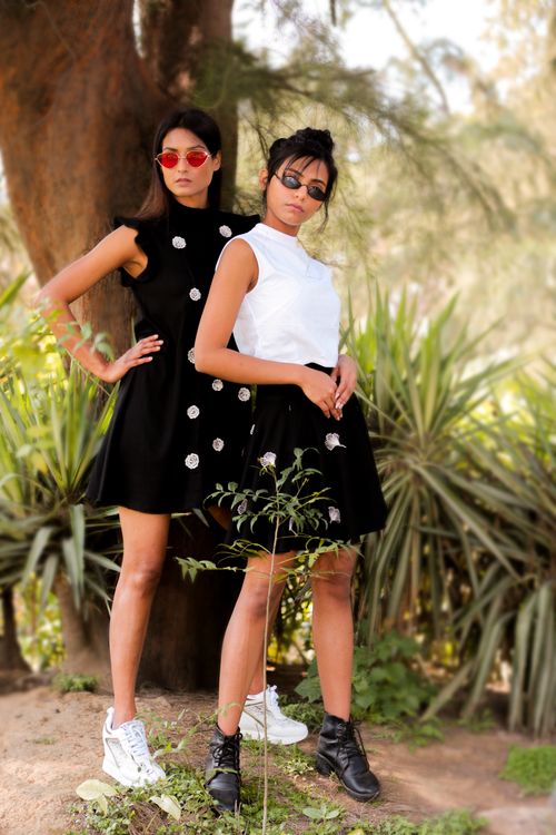 Free Stylish women in black dresses posing outdoors amid lush greenery in India. Stock Photo