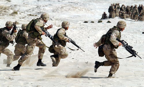 5 Soldiers Holding Rifle Running on White Sand during Daytime