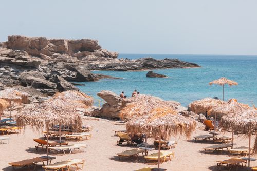 Free A scenic beach in Kallithea, Greece, featuring straw umbrellas and rocky formations by the sea. Stock Photo