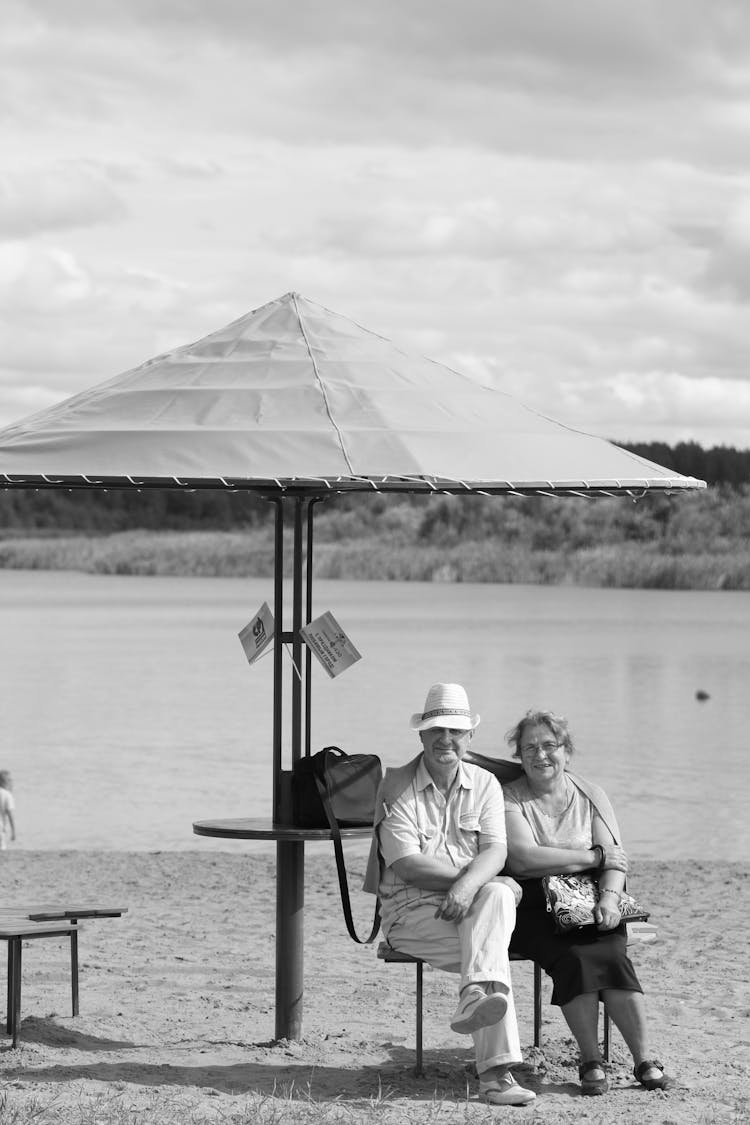 Couple Sitting Under An Umbrella On A Beach