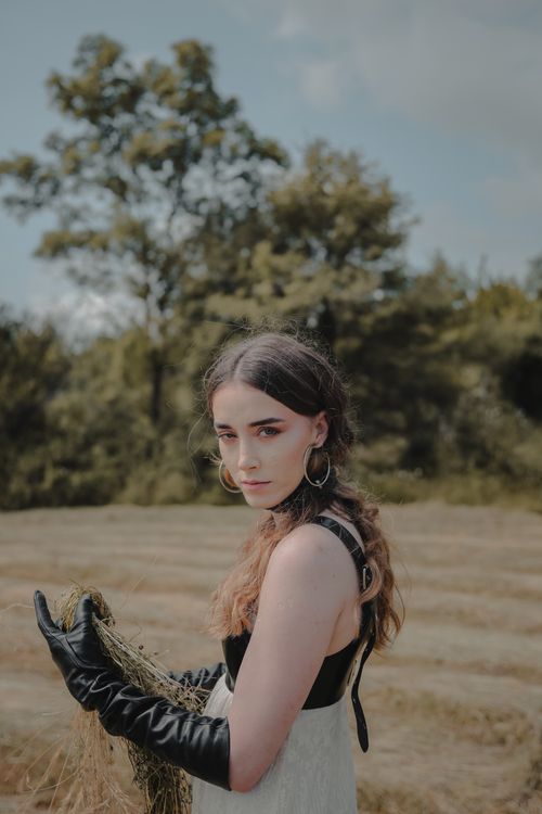 Free A woman in a corset with gloves holding hay in an open field. Stock Photo