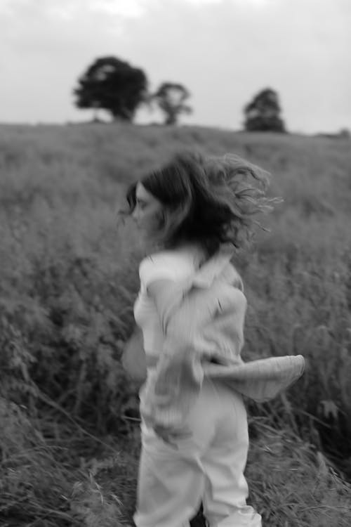 Grayscale Photo of a Woman Running in a Field