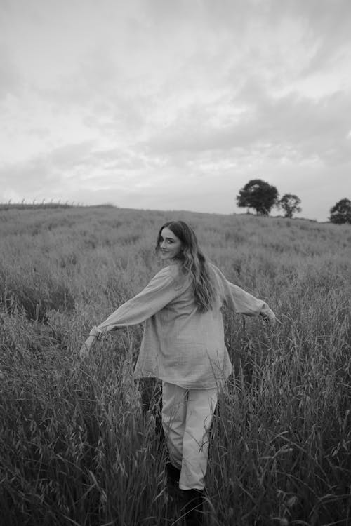 Free Grayscale Photo of a Woman Walking on a Grassy Field Stock Photo