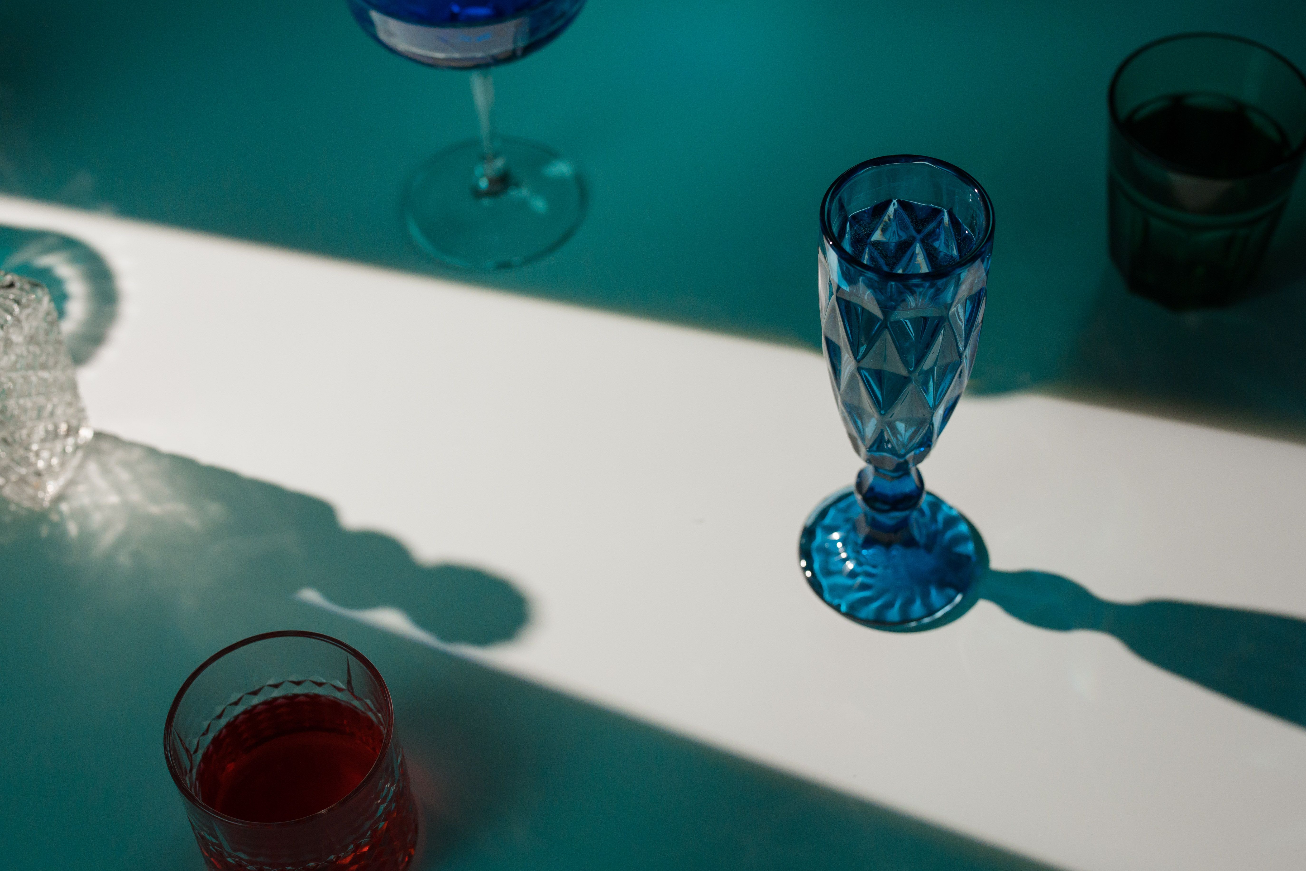 Elegant arrangement of colorful glassware casting dynamic shadows on a white surface.