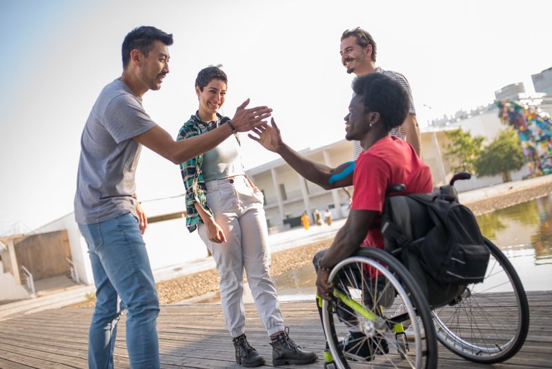 A friendly support group gathering in a community center, with people with different disabilities sharing stories.