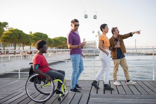 Free A diverse group of friends enjoying time together by a pier in Portugal, with a cable car in the background. Stock Photo
