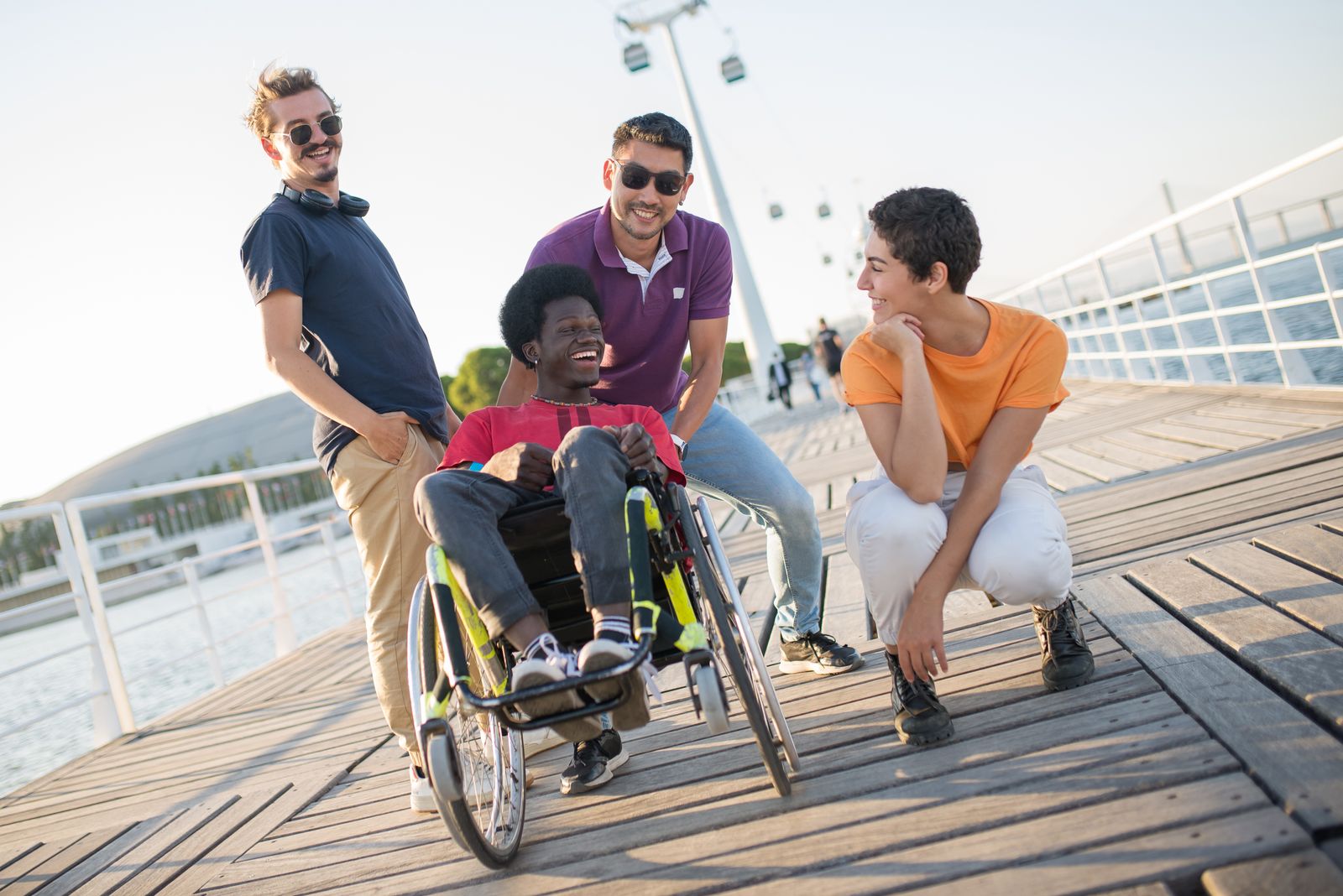 Young adult friends, including a wheelchair user, laughing together outdoors