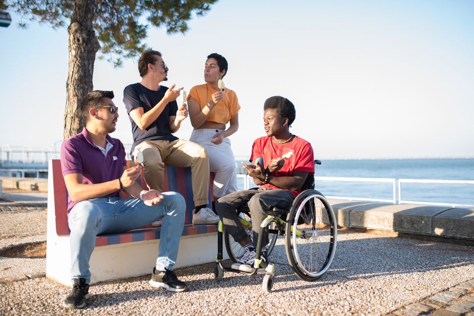 Un grupo diverso de amigos sentados al aire libre junto al mar, disfrutando de helado y socializando.
