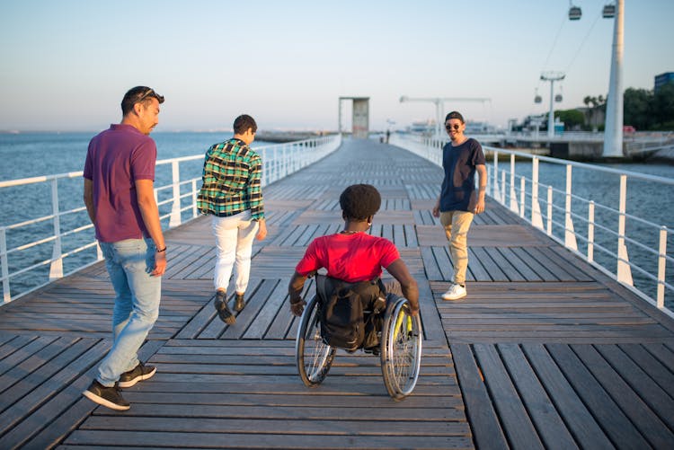 A Group Of Friends Strolling Along The Harbor Boardwalk