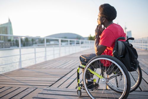 Free Man in wheelchair enjoying sunny day on a scenic boardwalk in Portugal. Stock Photo