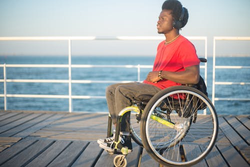 Man in Wheelchair Wearing Headphones in Seaside