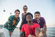 Group of friends smiling and having fun at a waterfront in Portugal, capturing joyful moments together.