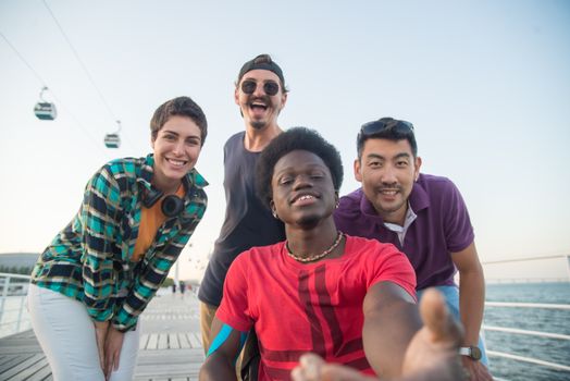 Group of friends smiling and having fun at a waterfront in Portugal, capturing joyful moments together.