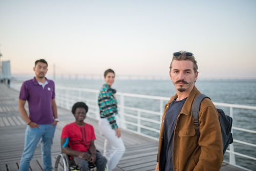 Free Diverse group of friends enjoying a sunset walk on a scenic pier in Portugal. Stock Photo