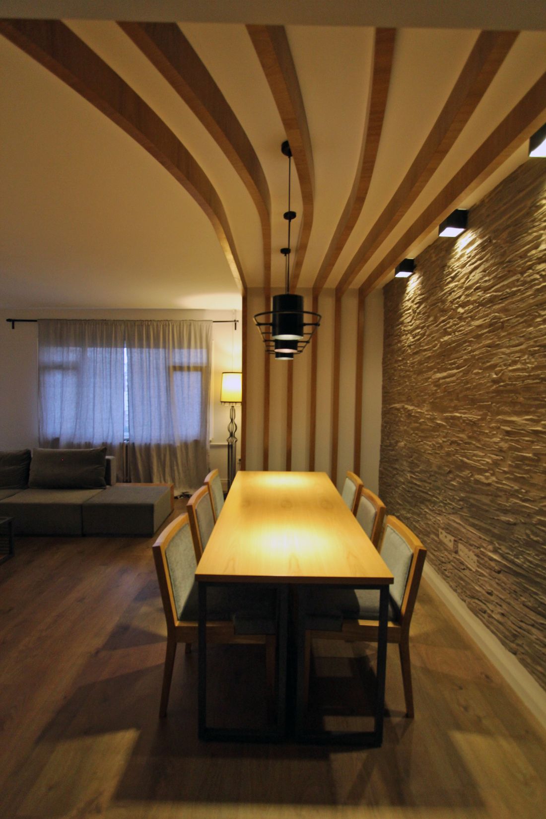 Pendant lights hung above a long dining table in a warm timber-lined room — photo by özhan Hazırlar on Pexels
