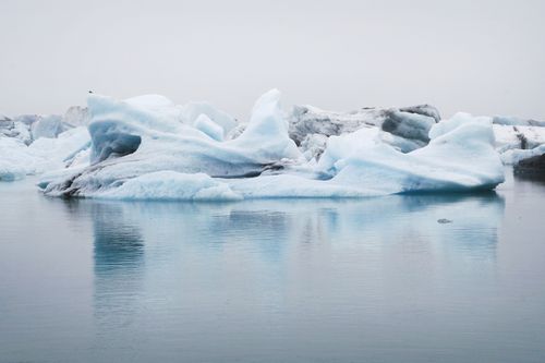 Free A majestic iceberg floating calmly in serene blue waters, embodying the essence of winter's chill. Stock Photo