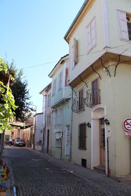 Free Discover the charm of Ayvalık's historic alley with pastel buildings and cobblestone street. Stock Photo