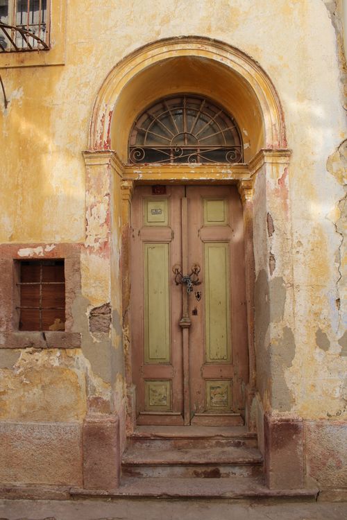 Free Vintage wooden door with arch in Ayvalık, Türkiye, showcasing rustic Mediterranean architecture. Stock Photo