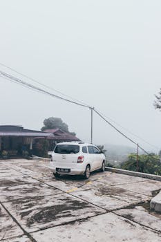 雾气缭绕的山区停车场里，停着一辆白色汽车，风景优美