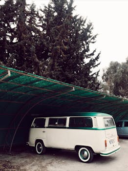Classic camper van parked under a canopy surrounded by trees, evoking a retro vibe.