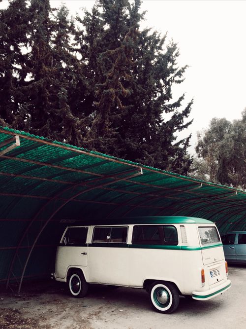 Free Classic camper van parked under a canopy surrounded by trees, evoking a retro vibe. Stock Photo