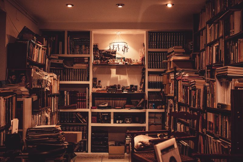Warmly lit home library full of books — photo by Juan Pablo Serrano on Pexels