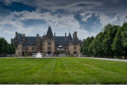 Stunning view of Biltmore Estate in Asheville with vibrant gardens and clear sky, showcasing architectural grandeur.