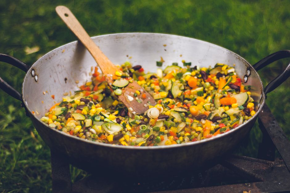 Mixed vegetables including corn, carrots, and peas cooking in a skillet`
